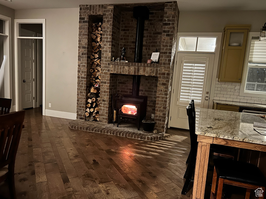 Living room with dark hardwood / wood-style floors, brick wall, and a wood stove