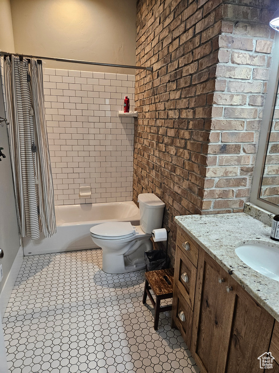 Full bathroom with shower / bath combo with shower curtain, vanity, brick wall, toilet, and tile flooring