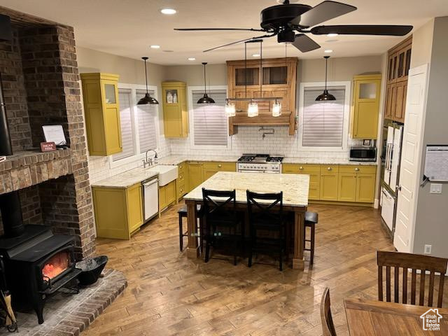 Kitchen with pendant lighting, light hardwood / wood-style flooring, a center island, and a wood stove