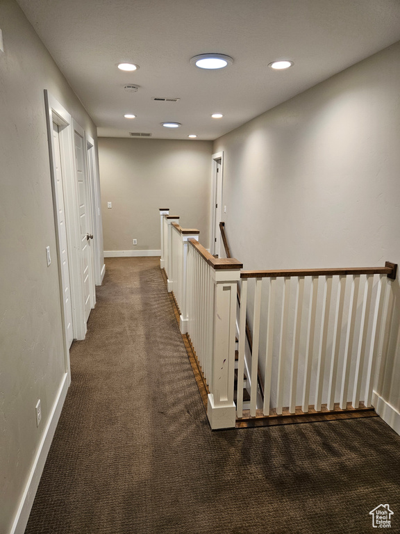 Corridor featuring dark carpet
