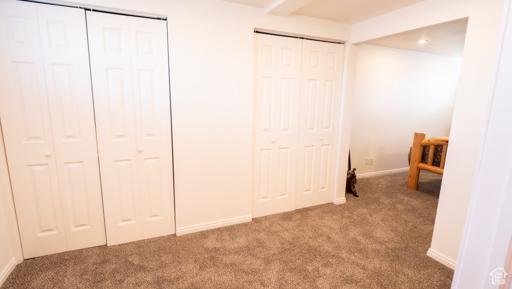 Interior space with dark colored carpet and multiple closets