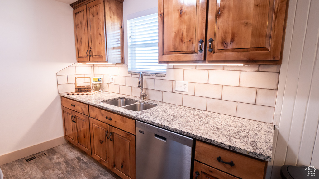 Kitchen featuring light stone countertops, dark hardwood / wood-style flooring, tasteful backsplash, stainless steel dishwasher, and sink