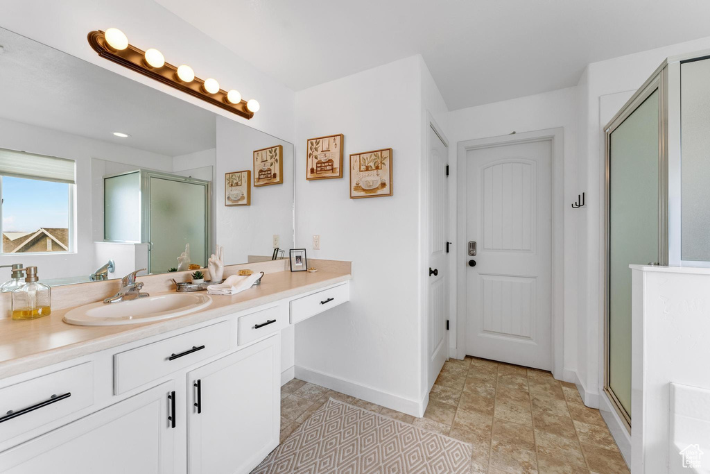 Bathroom featuring vanity, a shower with shower door, and tile flooring