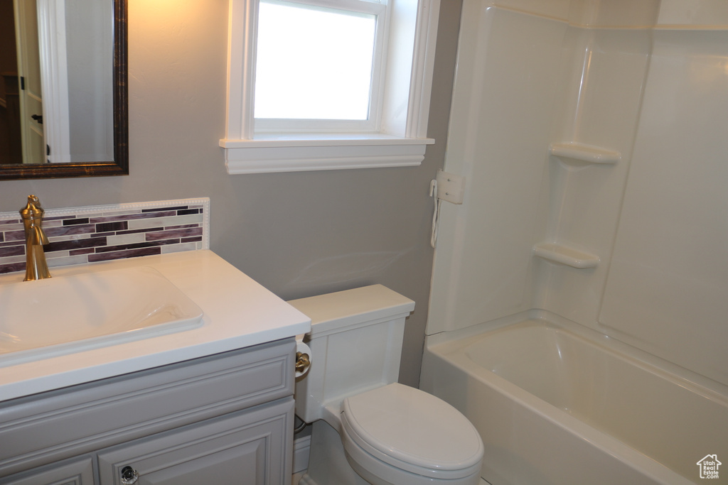 Full bathroom featuring vanity, toilet, tub / shower combination, and tasteful backsplash