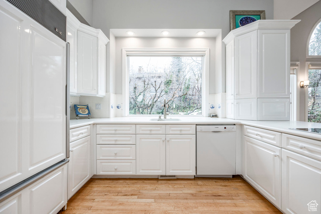 Kitchen with a wealth of natural light, light hardwood / wood-style floors, dishwasher, and white cabinets