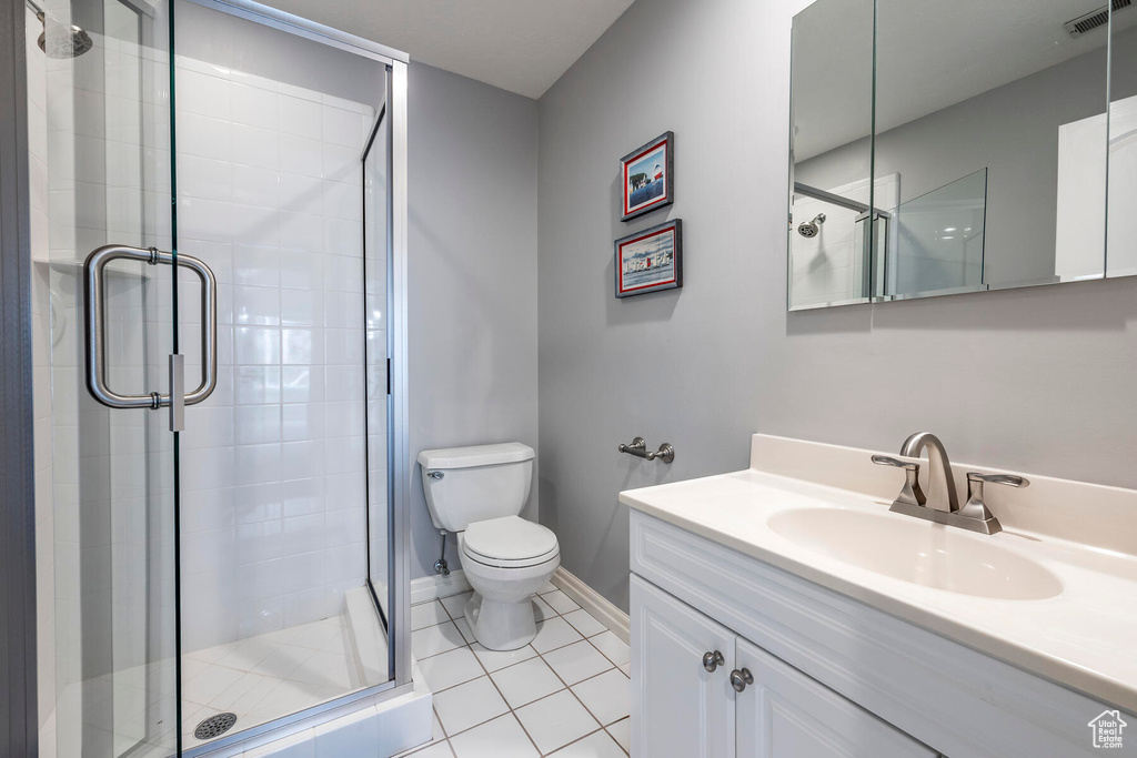 Bathroom featuring toilet, walk in shower, large vanity, and tile flooring