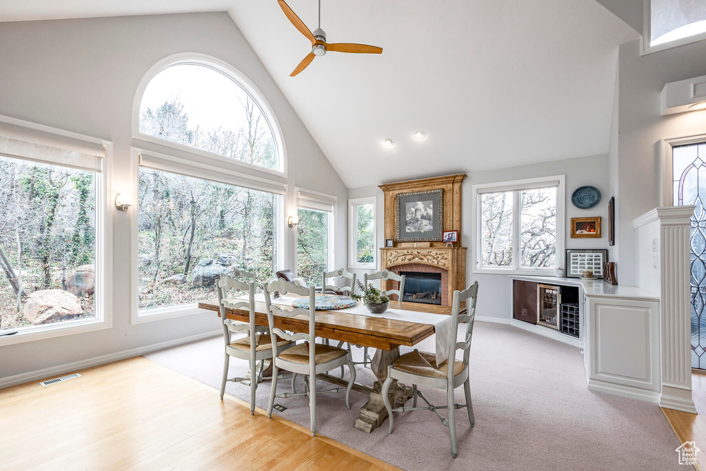 Carpeted dining room with high vaulted ceiling and ceiling fan