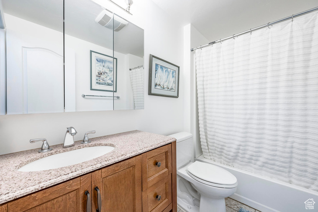 Full bathroom featuring tile floors, vanity, shower / bath combo, and toilet