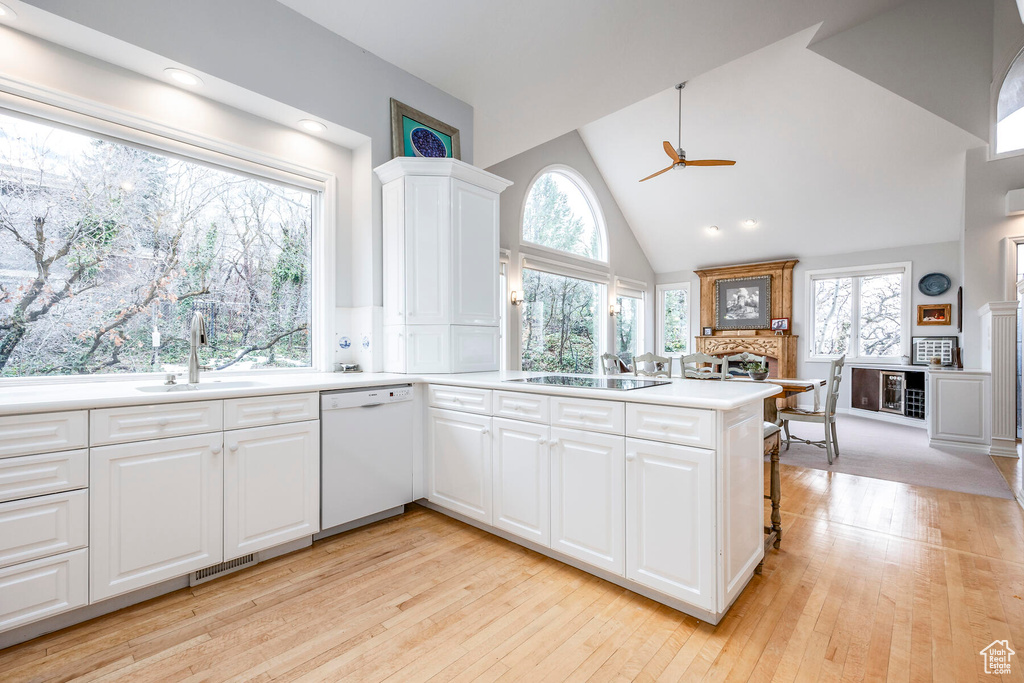 Kitchen with white dishwasher, ceiling fan, white cabinets, and light hardwood / wood-style floors