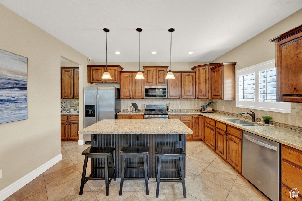 Kitchen featuring appliances with stainless steel finishes, a center island, backsplash, and sink