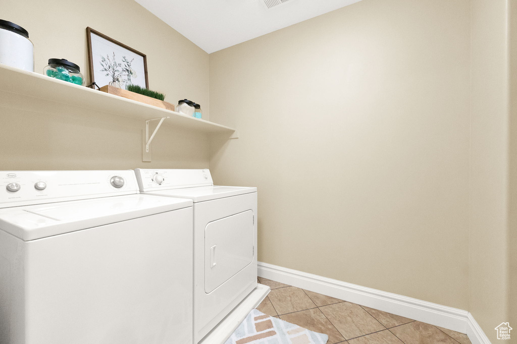 Clothes washing area with washer and clothes dryer and light tile floors