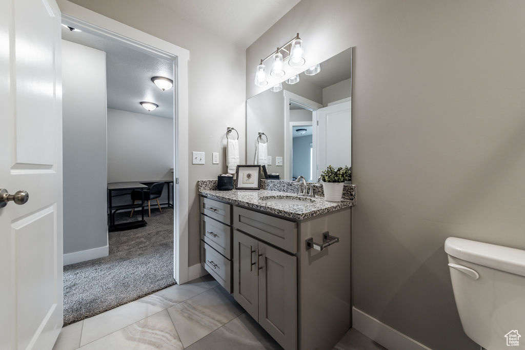 Bathroom with toilet, oversized vanity, and tile flooring