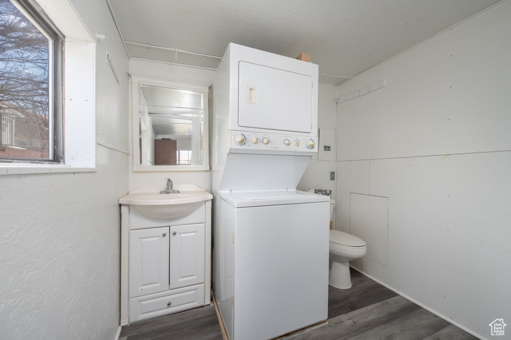 Bathroom featuring hardwood / wood-style floors, stacked washer and dryer, vanity, and toilet
