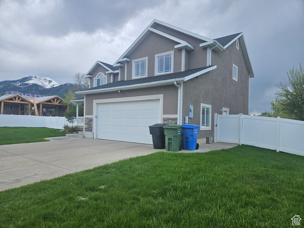 View of front of house featuring a mountain view, a front lawn, and a garage