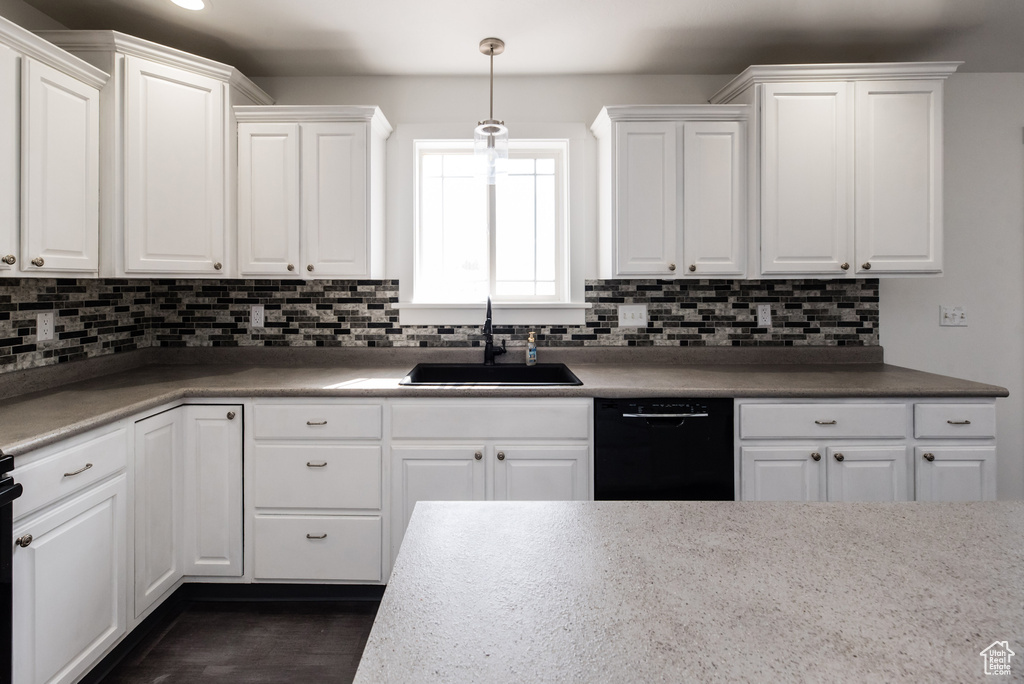 Kitchen with pendant lighting, white cabinetry, black dishwasher, sink, and backsplash