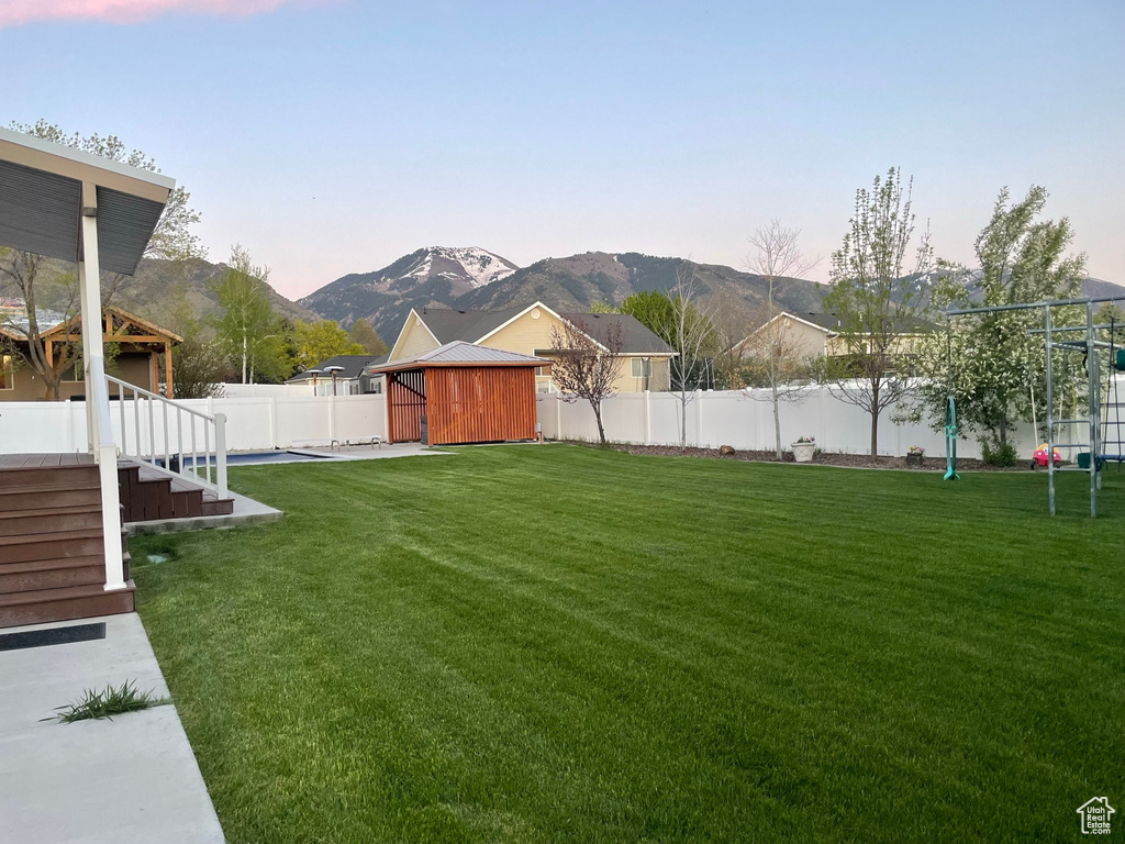 Yard at dusk with a mountain view and an outdoor structure