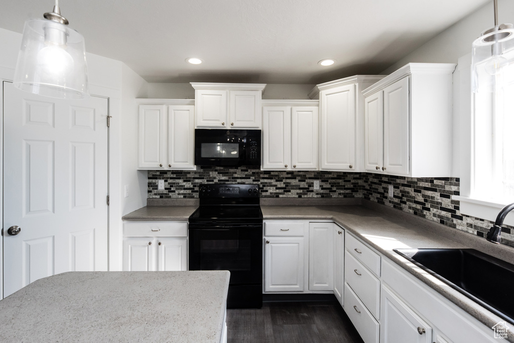 Kitchen featuring pendant lighting, dark hardwood / wood-style flooring, white cabinets, and black appliances