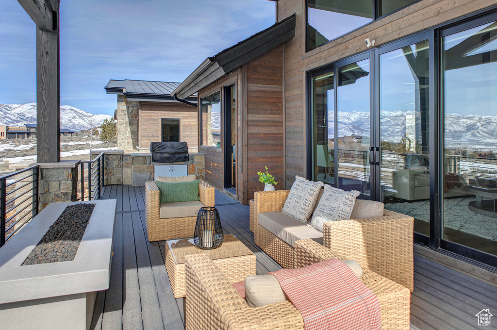 Snow covered deck with an outdoor hangout area and a mountain view