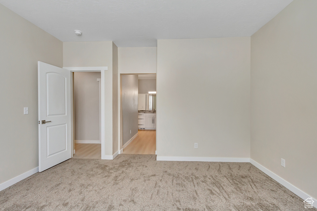 Unfurnished bedroom featuring light colored carpet and ensuite bath