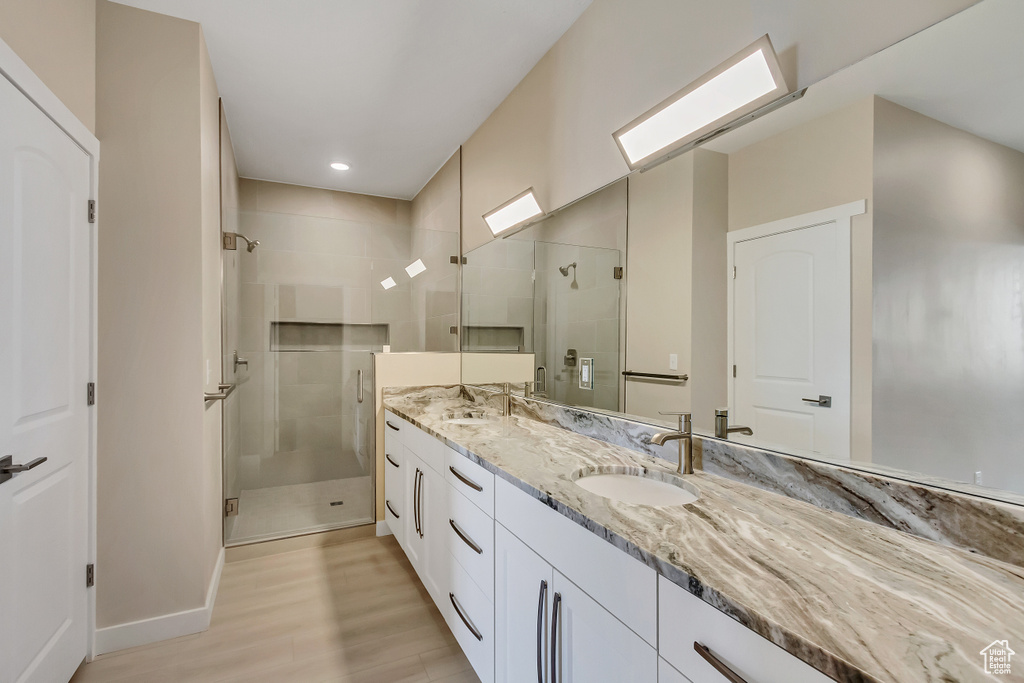 Bathroom featuring a shower with shower door, hardwood / wood-style flooring, and dual vanity