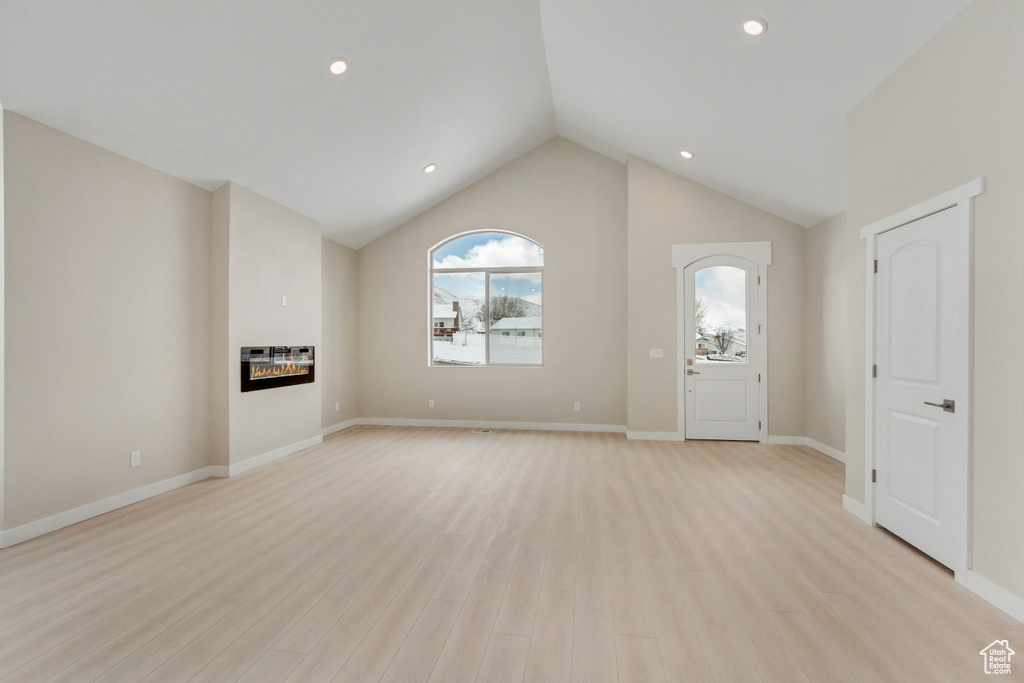 Entrance foyer with light hardwood / wood-style floors and lofted ceiling