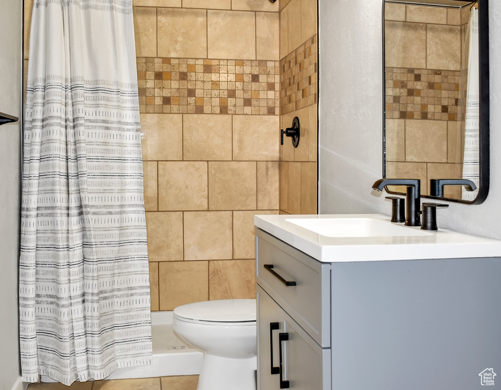 Bathroom featuring vanity, a shower with shower curtain, toilet, tile floors, and tile walls