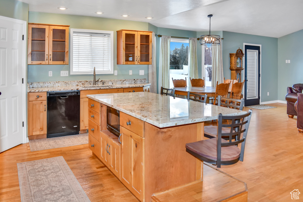 Kitchen with dishwasher, light hardwood / wood-style floors, pendant lighting, a kitchen island, and a chandelier