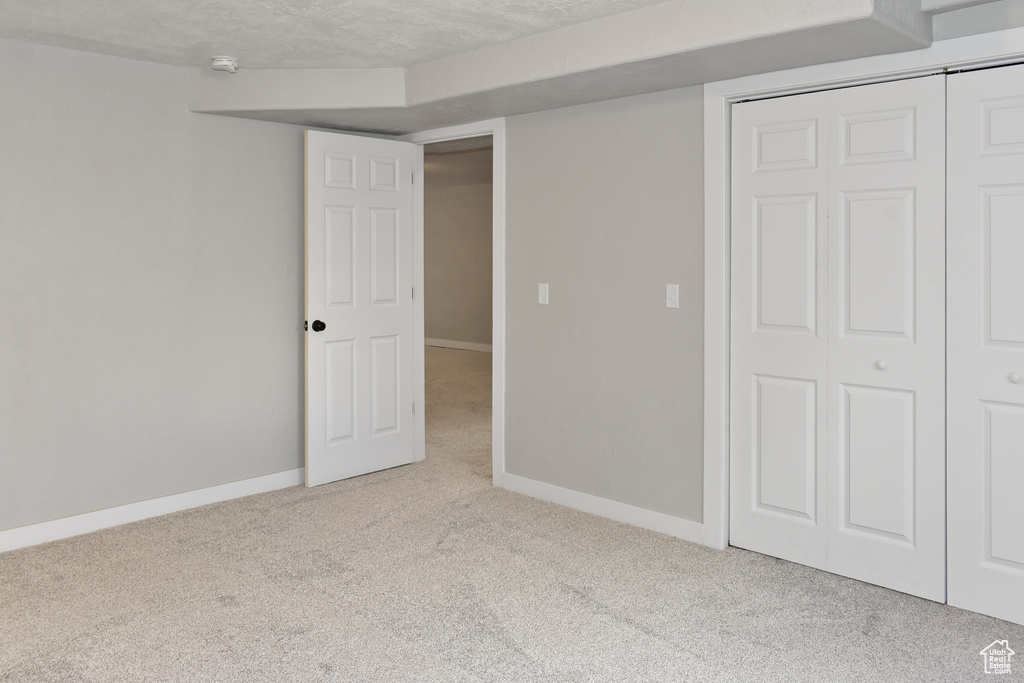 Unfurnished bedroom featuring a closet, light colored carpet, and a textured ceiling