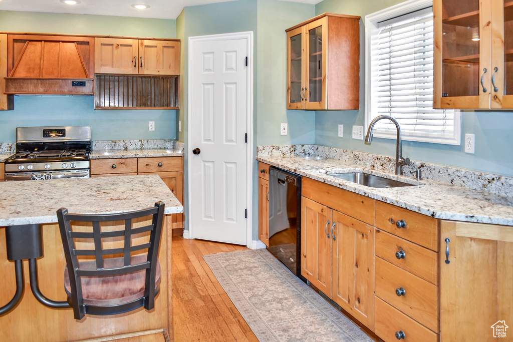 Kitchen featuring light hardwood / wood-style floors, dishwasher, gas stove, custom range hood, and sink