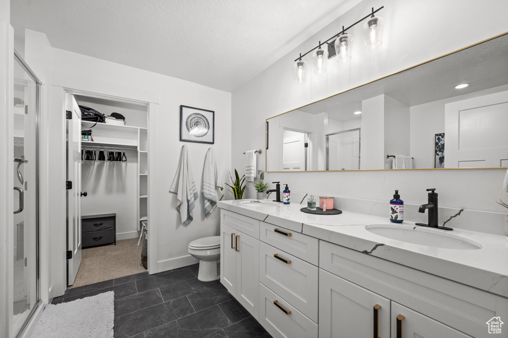 Bathroom with large vanity, double sink, toilet, and tile flooring