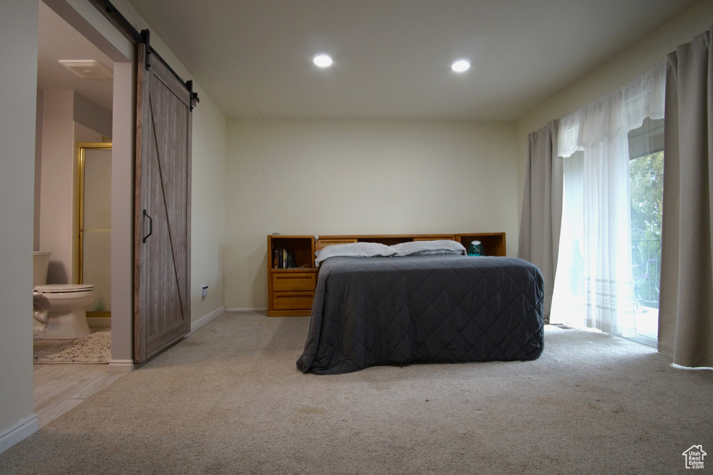 Carpeted bedroom with connected bathroom, access to outside, and a barn door