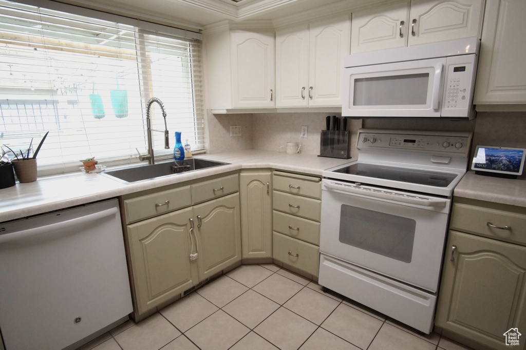 Kitchen with ornamental molding, tasteful backsplash, sink, light tile floors, and white appliances
