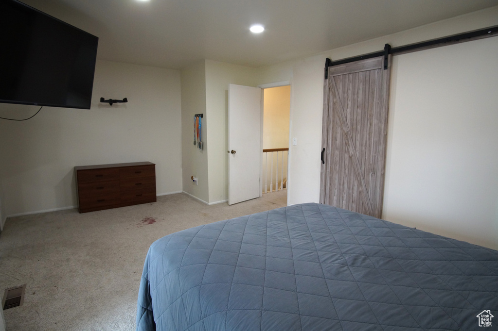 Bedroom featuring a barn door and light colored carpet