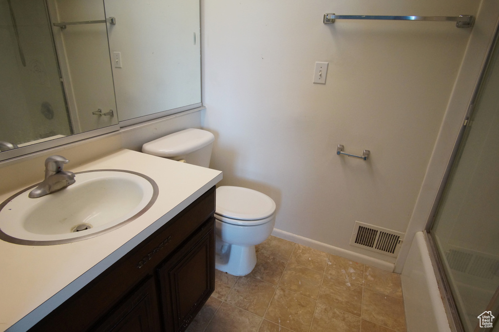 Full bathroom featuring shower / bath combination with glass door, tile flooring, oversized vanity, and toilet
