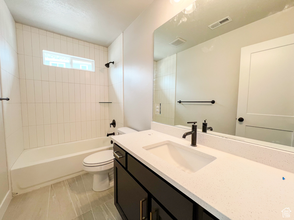 Full bathroom with tile flooring, vanity, toilet, and tiled shower / bath