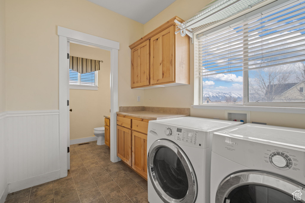 Washroom featuring hookup for a washing machine, washer and dryer, dark tile flooring, and cabinets