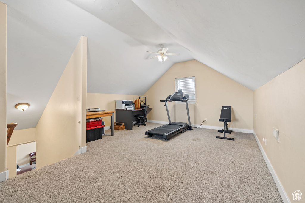 Workout room with ceiling fan, light carpet, and lofted ceiling
