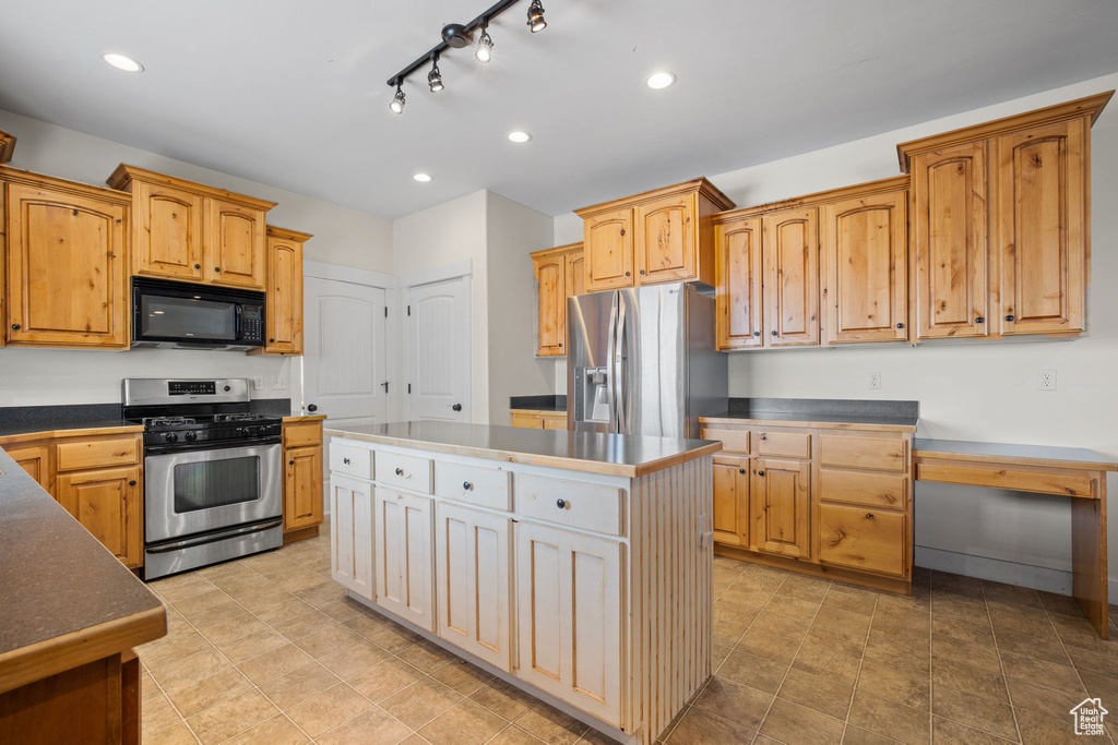 Kitchen with a center island, light tile floors, stainless steel appliances, and track lighting