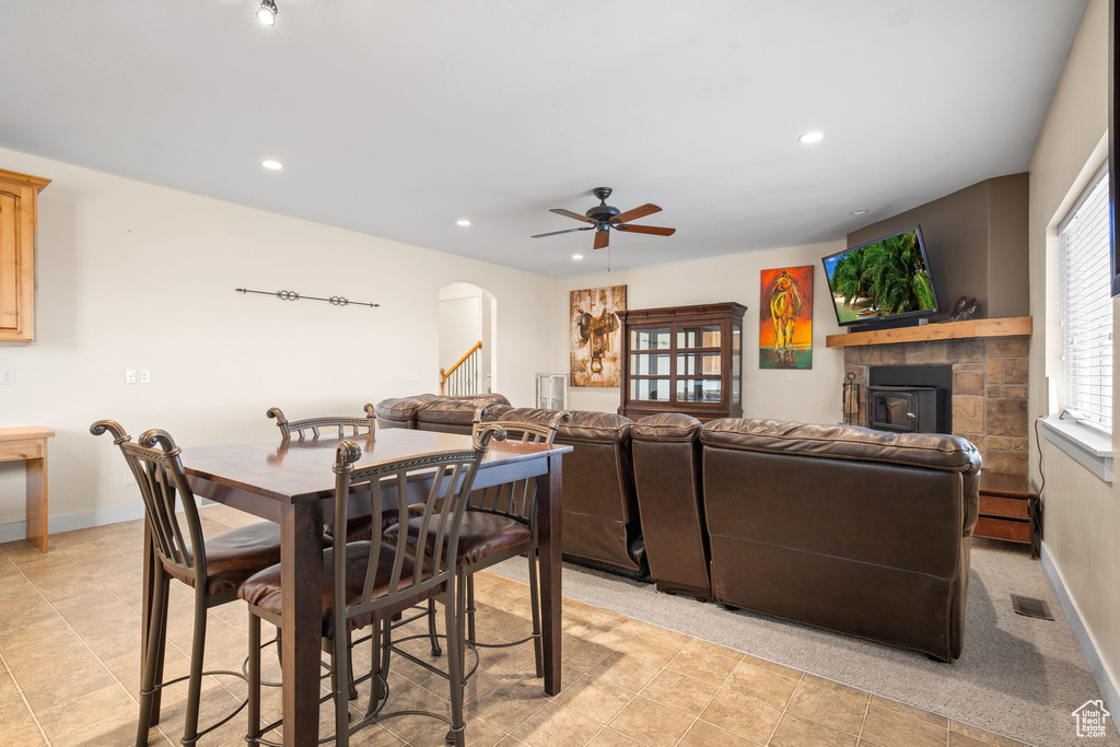 Dining space with baseboard heating, a tiled fireplace, light tile floors, and ceiling fan