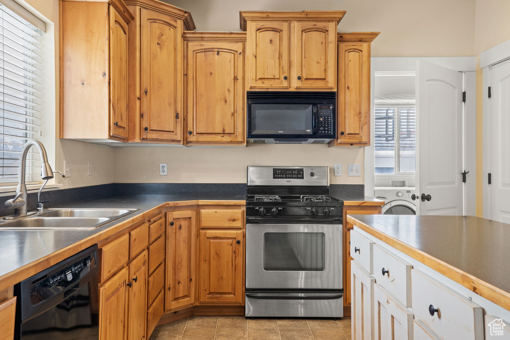 Kitchen featuring stainless steel gas stove, light tile floors, dishwasher, washer / clothes dryer, and sink