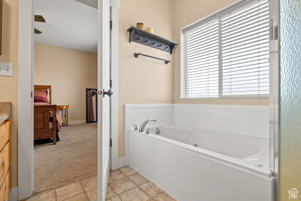 Bathroom with a wealth of natural light, vanity, tile floors, and a tub