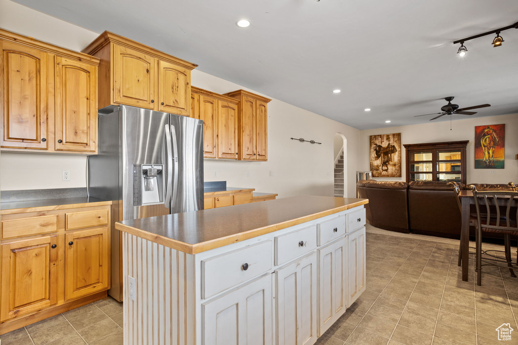 Kitchen featuring light tile floors, stainless steel fridge with ice dispenser, ceiling fan, track lighting, and a center island