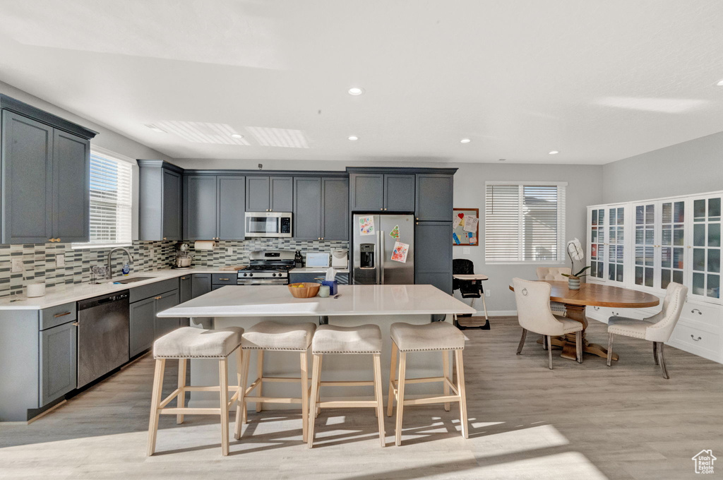 Kitchen featuring a kitchen island, appliances with stainless steel finishes, a breakfast bar, and light hardwood / wood-style floors