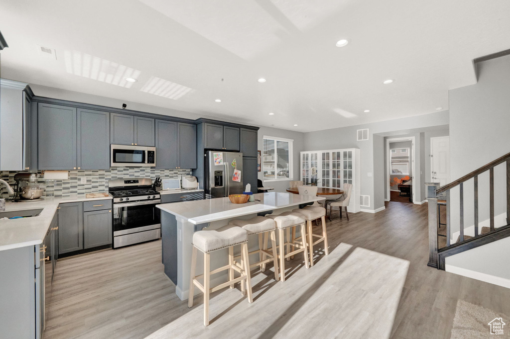 Kitchen featuring appliances with stainless steel finishes, light hardwood / wood-style flooring, a center island, and gray cabinets