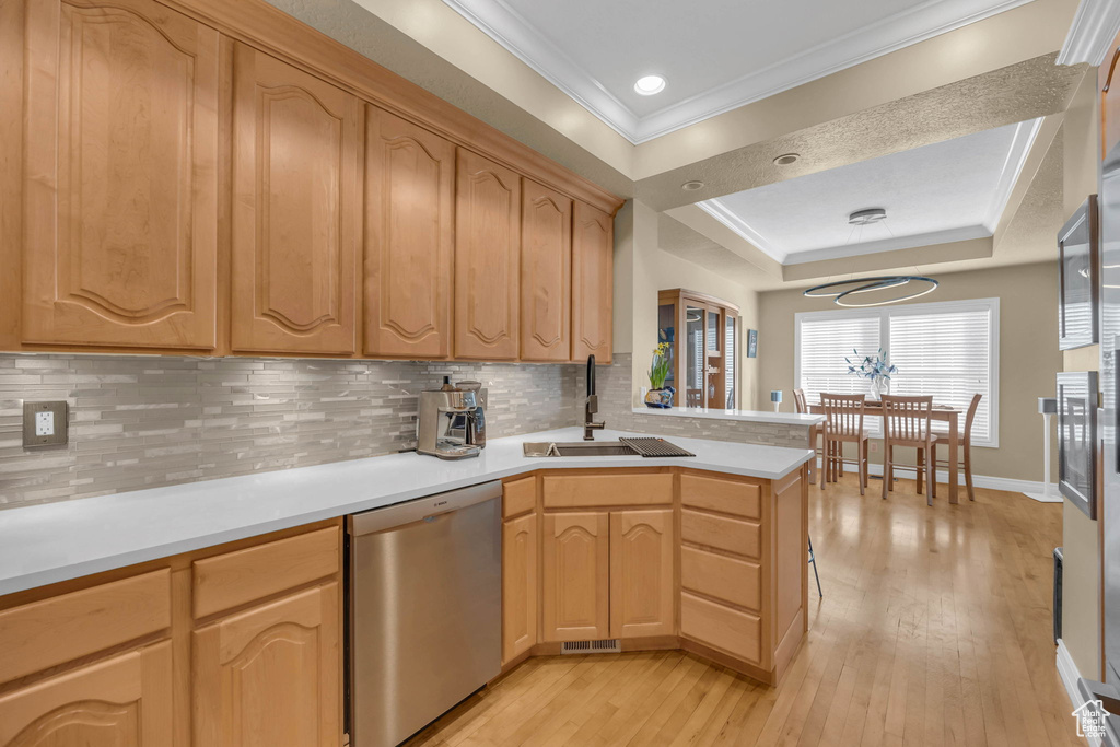 Kitchen with light hardwood / wood-style floors, dishwasher, ornamental molding, tasteful backsplash, and sink
