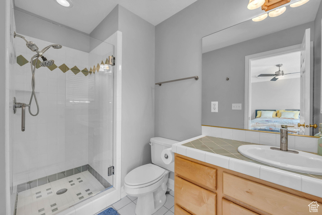 Bathroom with ceiling fan, a shower with door, oversized vanity, toilet, and tile flooring