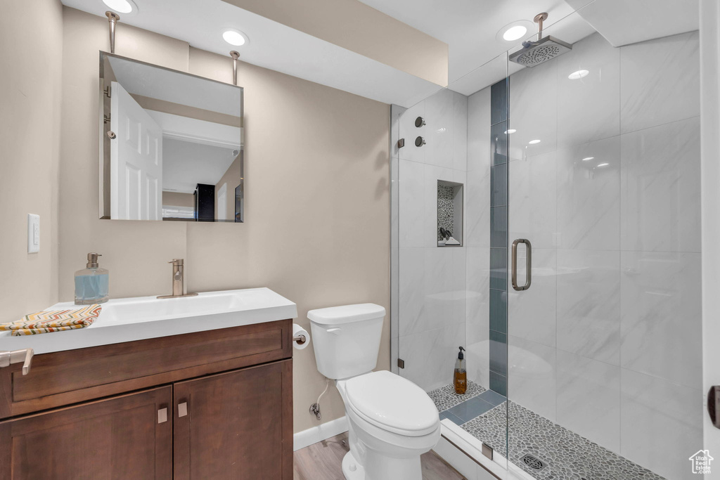 Bathroom featuring a shower with shower door, hardwood / wood-style flooring, vanity, and toilet