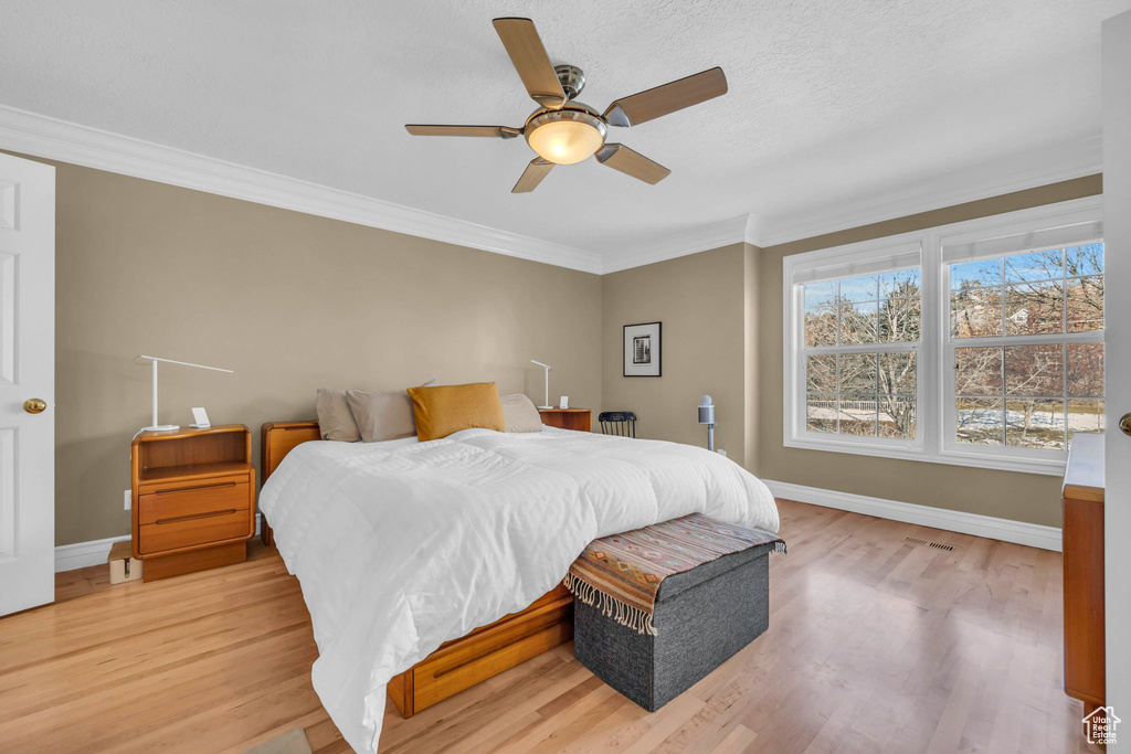 Bedroom with light wood-type flooring, crown molding, and ceiling fan