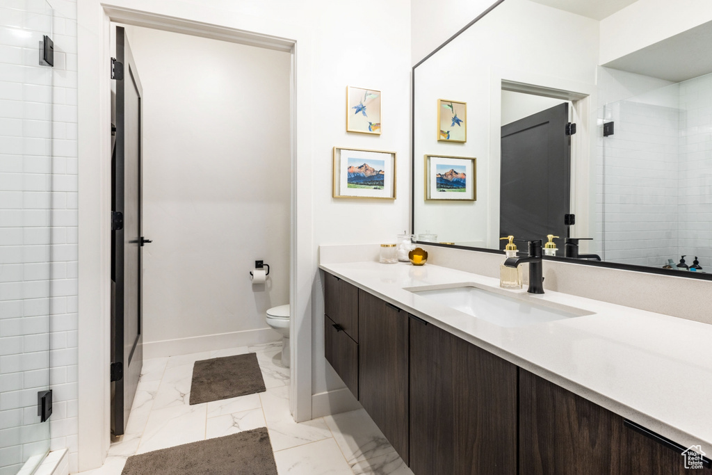 Bathroom featuring tile flooring, toilet, vanity, and tiled shower