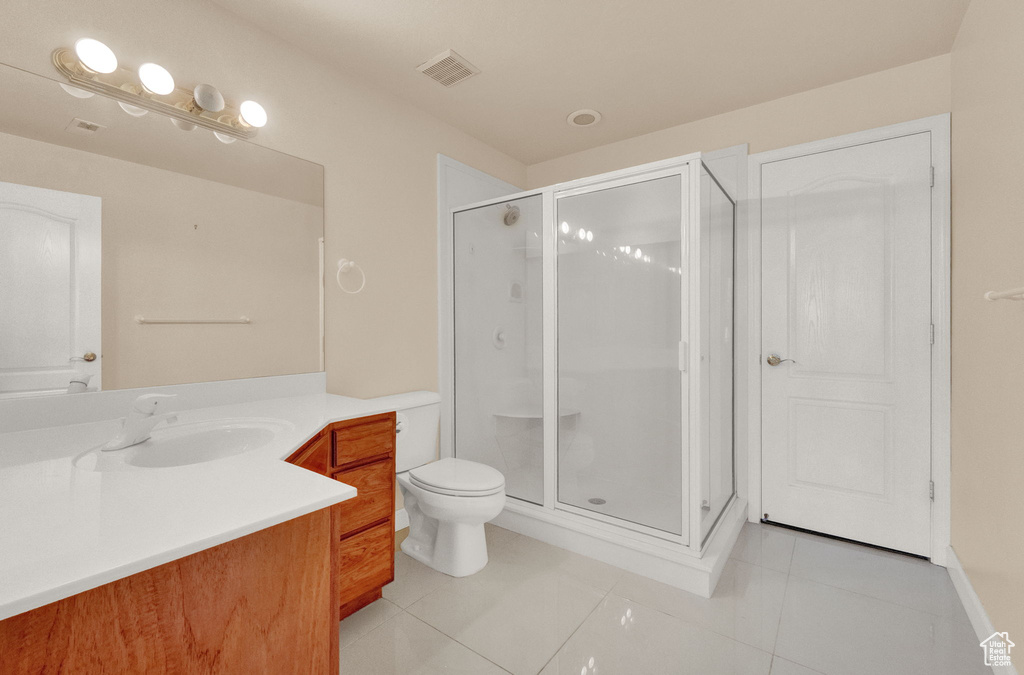 Bathroom featuring vanity, toilet, a shower with door, and tile flooring